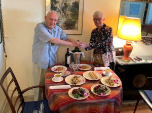 Dick Graham and Jane McKeel stand over the special dinner laid out on their dining room table to celebrate Dick's 25th year at GHBC. 